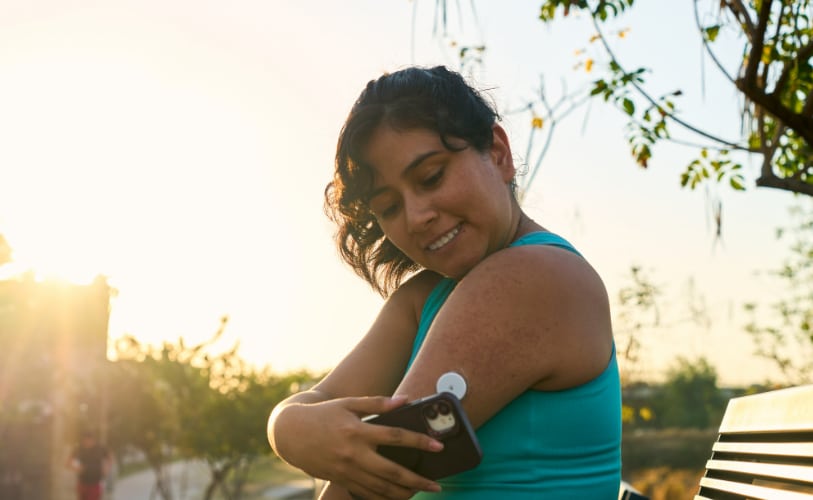 Woman applying a glucose sensor to her arm